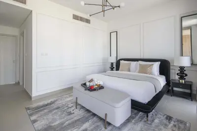 a white bedroom with a large bed and a table at Frank Porter - Club Villas in Dubai