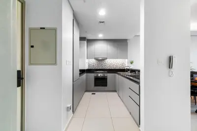 a kitchen with white cabinets and a white floor at Sky-High 2BR - Infinity Pool & Burj Khalifa Views in Dubai