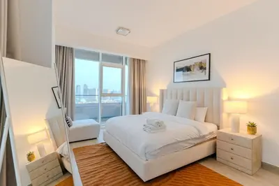 a bedroom with a white bed and a large window at Spacious l Opened View l Fits 4 in Dubai