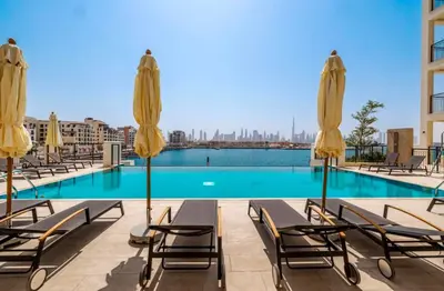 a swimming pool with chairs and umbrellas at Sea View l Port De LaMer l Next to Beach l Perfect for 4 in Dubai