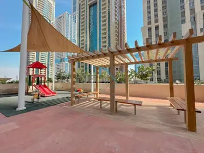 a park with benches and a playground with tall buildings at Serene 2BR with Iconic Palm Jumeirah Views, Dubai Marina by Deluxe Holiday Homes in Dubai