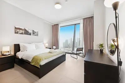 a bedroom with a bed and a desk and a window at 3BR Family abode with Iconic Burj Khalifa view in Dubai