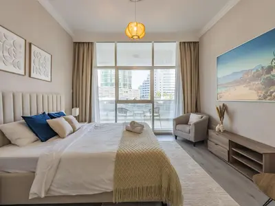 a bedroom with a large bed and a chair at The 'Mallorca' Condo - JBR Beachfront Stay in Dubai