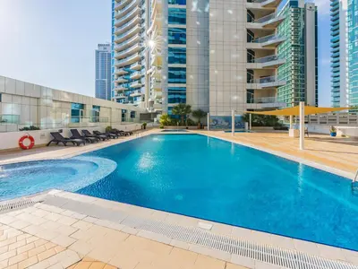 a large swimming pool in a building with tall buildings at The 'Mallorca' Condo - JBR Beachfront Stay in Dubai