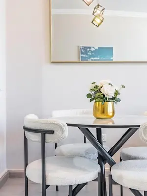 a dining room table with chairs and a vase of flowers at The 'Mallorca' Condo - JBR Beachfront Stay in Dubai