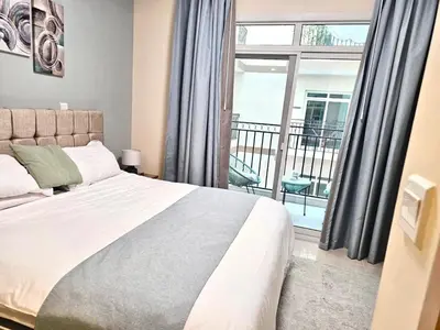 a bedroom with a large bed and a balcony at Deluxe 1BHK Apt in JVC, Self check in ! in Dubai