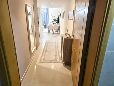 a hallway leading to a living room with a table at Deluxe 1BHK Apt in JVC, Self check in ! in Dubai