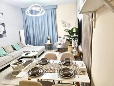 a living room with a couch and a table and chairs at Deluxe 1BHK Apt in JVC, Self check in ! in Dubai