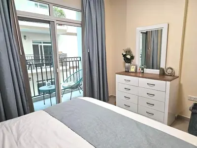 a bedroom with a bed with a dresser and a balcony at Deluxe 1BHK Apt in JVC, Self check in ! in Dubai