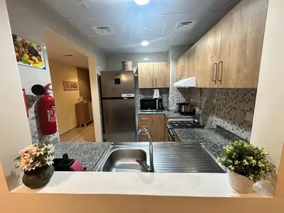a kitchen with a sink and a stainless steel refrigerator at Deluxe 1BHK Apt in JVC, Self check in ! in Dubai