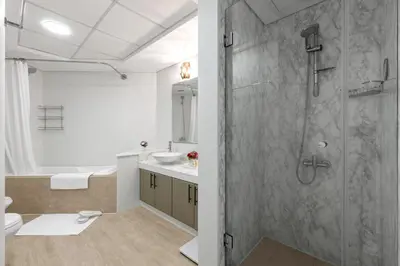 a bathroom with a shower and a toilet and a sink at Spacious 2BR with Pool & Private Beach Access in Dubai