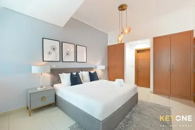 a bedroom with a large white bed and a cabinet at Fascinating Ocean Views in a One Bedroom in Dubai