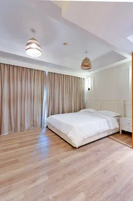 a bedroom with a large white bed and wooden floors at Modern Studio I Boulevard View I Downtown Dubai in Dubai