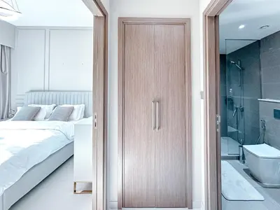 a bedroom with a wooden door next to a bed and a bathroom at Amazing 1 Bedroom in Burj Royale Downtown in Dubai