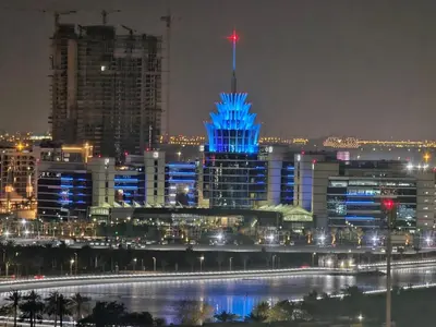 a city skyline at night with a blue building at Dubai Silicon Oasis Staycation in Dubai
