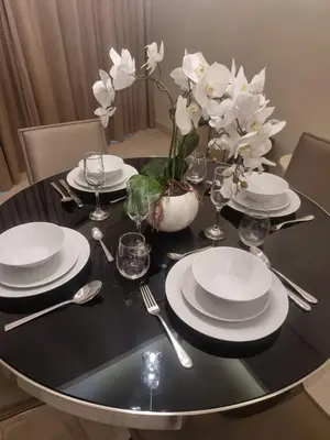 a black table with white plates and silverware and flowers on it at 1 Bedroom Tower D Paramount Apt in Dubai