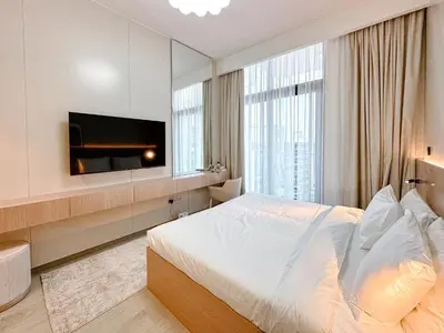a bedroom with a bed and a flat screen tv at Cozy Studio in Azizi Riviera with Balcony in Meydan City in Dubai