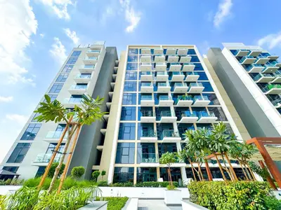 a tall building with palm trees in front of it at Cozy Studio in Azizi Riviera with Balcony in Meydan City in Dubai