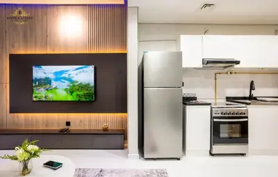 a kitchen with a refrigerator and a tv on the wall at Modern Studio at The Crescent Tower B, IMPZ - In the heart of Dubai in Dubai