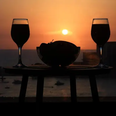 two glasses of wine and a bowl on a table with the sunset at Cozy Dubai Eye & Sunset Views - JBR Beachfront - Gym & Pool - Free Parking in Dubai
