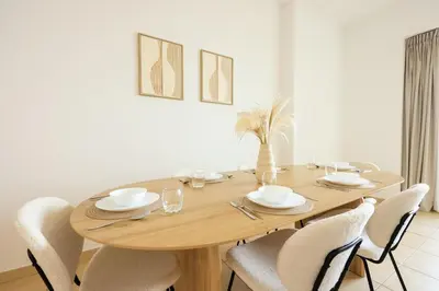 a dining room table with white chairs and a wooden table at Cozy Dubai Eye & Sunset Views - JBR Beachfront - Gym & Pool - Free Parking in Dubai