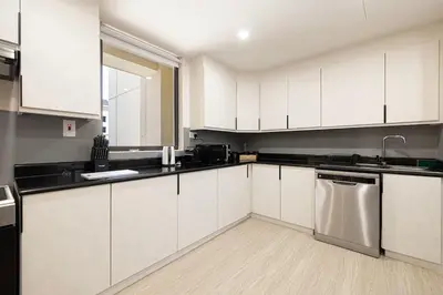 a kitchen with white cabinets and a stainless steel dishwasher at FIRST CLASS 2BR Breathtaking Beach Views in Dubai