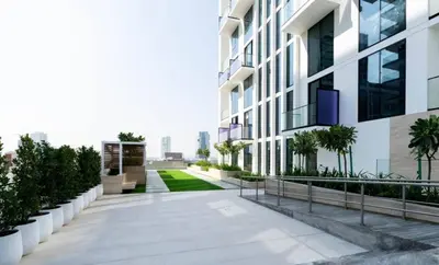 a walkway leading to a building with plants at Bright 1br Jvc Balcony & Free Parking in Dubai