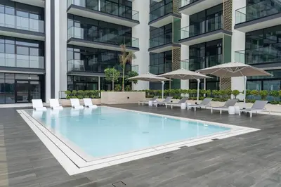 a swimming pool in a building with chairs and umbrellas at Comfortable 1br In Jvc Balcony Free Parking in Dubai