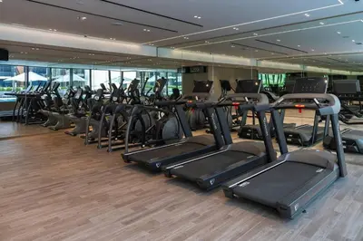a gym with rows of cardio equipment in a building at Modern 1br In Jvc Balcony, Pool & Parking in Dubai
