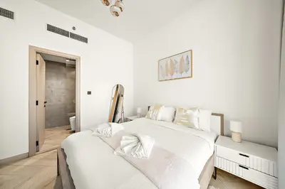 a white bedroom with a large bed with white sheets at Elegant 1 BR in Empire Residence in Dubai