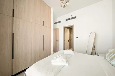 a bedroom with a white bed and wooden cabinets at Elegant 1 BR in Empire Residence in Dubai