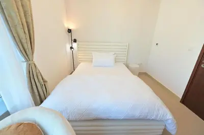 a small bedroom with a white bed and a window at La Vista Holiday Home with burj khalifa & fountain view in Dubai