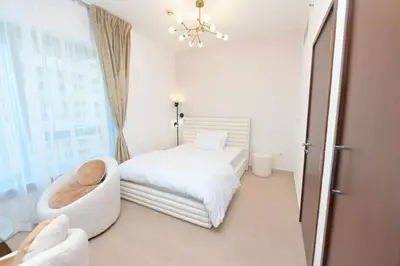 a bedroom with a bed and a chair and a window at La Vista Holiday Home with burj khalifa & fountain view in Dubai