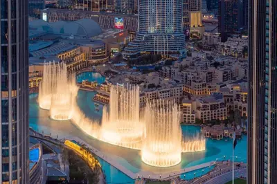a group of fountains in a city at night at La Vista Holiday Home with burj khalifa & fountain view in Dubai