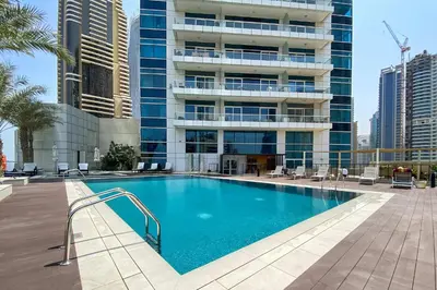 a swimming pool in front of a tall building at Silkhaus Comfy 1BR in Botanica Tower near Dubai Marina in Dubai