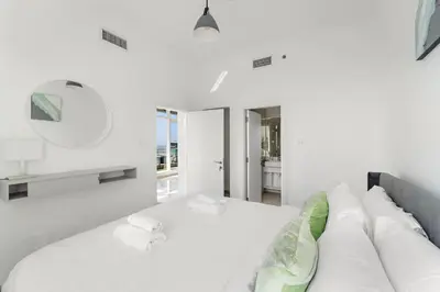 a white bedroom with a couch and a mirror at Silkhaus Comfy 1BR in Botanica Tower near Dubai Marina in Dubai