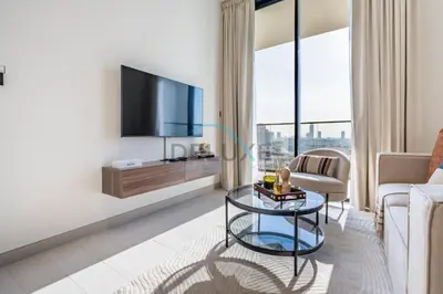 a living room with a tv and a couch and a table at Cozy 1BR with Balcony in Binghatti House, Jumeirah Village Circle by Deluxe Holiday Homes in Dubai