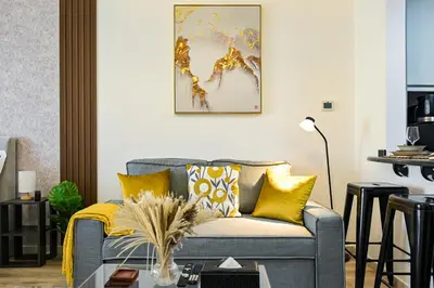 a living room with a gray couch with yellow pillows at Modern Studio in Discovery Gardens, Close to Metro in Dubai