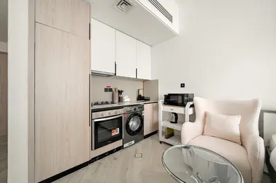 a kitchen with a couch and a chair in a room at Cozy Studio in Empire Residence in Dubai