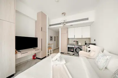 a living room with a white couch and a tv at Cozy Studio in Empire Residence in Dubai