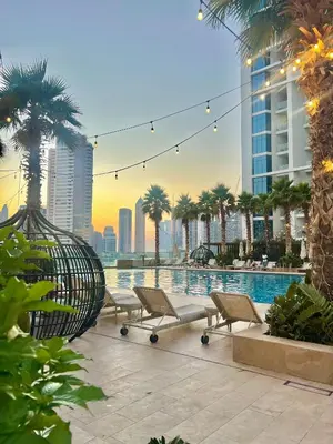 a pool with lounge chairs and palm trees in a city at Luxury Studio Near Burj Khalifa in Dubai