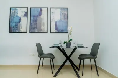 a table with four chairs in a room with paintings at King 1BR Apartment With Burj Khalifa & Fountain View in Dubai