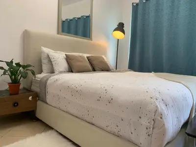 a bedroom with a white bed with a blue curtain at Cozy home marina in Dubai