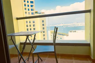 a table and chair in a balcony with a view of the ocean at ROYAL BEACH RESiDENCES 1 in Dubai