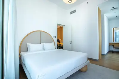 a bedroom with a white bed with a wooden headboard at Mood Living 45 in Dubai