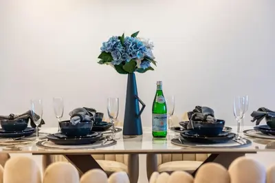 a table with a bottle of wine and a vase with flowers at The Smart Concierge - Princess tower in Dubai