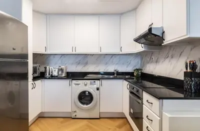 a kitchen with white cabinets and a washing machine at The Smart Concierge - Princess tower in Dubai