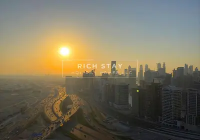a view of a city with the sun rising over a freeway at Sleek 2BR in Nobles, Business Bay in Dubai
