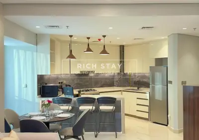 a kitchen with a table and chairs and a kitchen with a richstay sign at Sleek 2BR in Nobles, Business Bay in Dubai