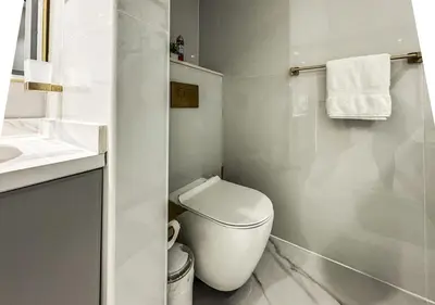 a white bathroom with a toilet and a sink at DreamShoma -2BR Deluxe Downtown Skyview in Dubai